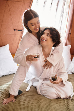 Two young lovers share laughter and warmth while relaxing, sipping drinks, in a tranquil setting.の写真素材