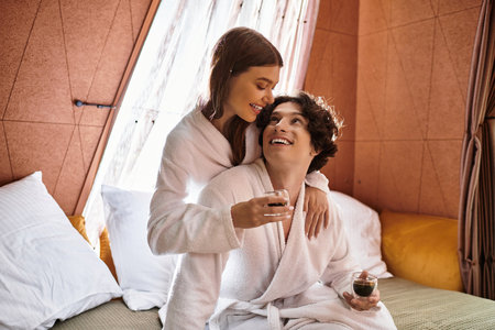 A young couple embraces warmly, sharing a joyful moment in a comfortable, intimate space.の写真素材