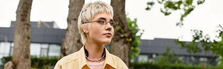 A beautiful young woman with a trendy haircut stands relaxed in a sunny park, embracing nature.の写真素材