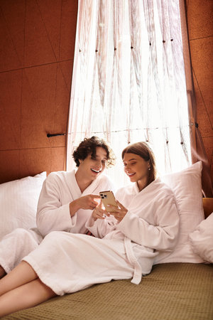 A young couple in fluffy robes shares laughs and connects during their relaxation time.の写真素材