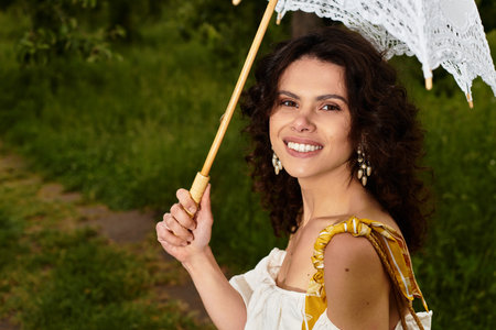 A young woman with curly hair enjoys a sunny day in the park in a white summer dress.の写真素材