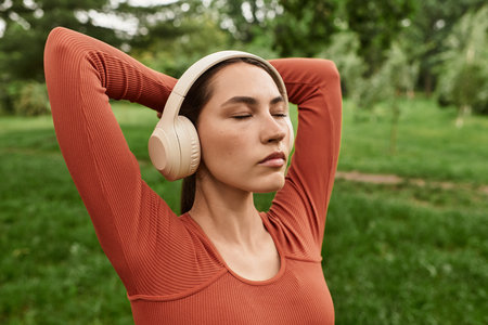 A young yoga teacher meditates outdoors with headphones, connecting to nature.の写真素材