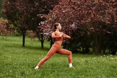 A young woman teaches yoga in a serene park, showcasing strength and balance in nature.の写真素材