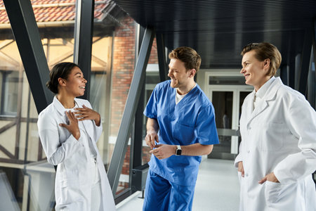 Cheerful doctors engage in a lively discussion in a well-lit hospital corridor.の写真素材