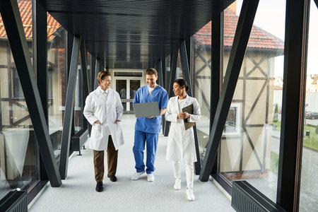 Three doctors in white coats discuss patient care in a hospital corridor.
