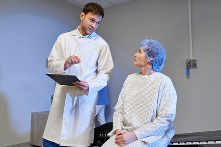 A doctor in a white coat explains the MRI process to a female patient in a hospital room.の写真素材
