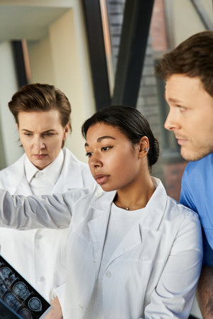 Three dedicated doctors discuss a patients medical scan in a contemporary hospital environment.の写真素材