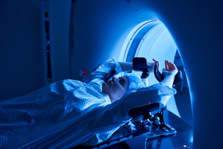 A woman lies in an MRI machine, surrounded by a tranquil blue ambiance, in a contemporary hospital.の写真素材