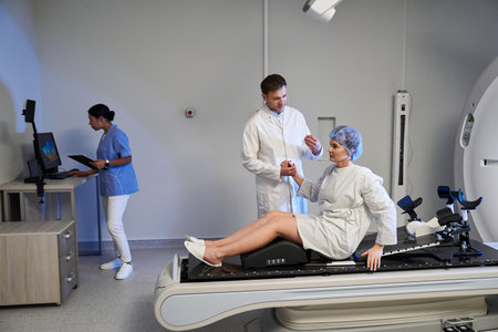 A skilled doctor and compassionate nurse prepare a woman for an MRI scan in a modern hospital.の写真素材