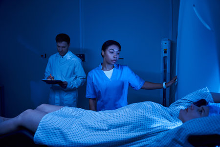 Handsome doctor and nurse assist a female patient preparing for an MRI scan in a modern facility.の写真素材