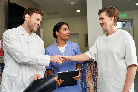 Healthcare team supports a female patient in a hospital, shaking hands with doctorの写真素材