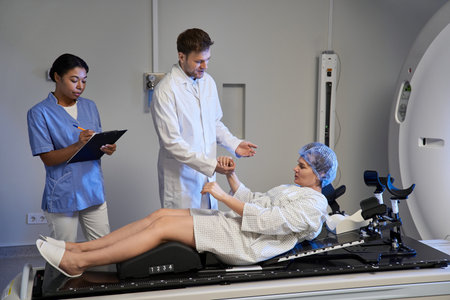 Doctor and nurse assist a female patient inside an MRI machine at a healthcare facility.の写真素材