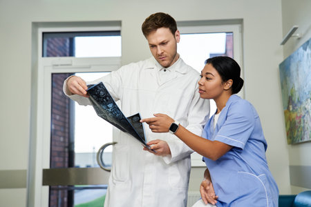 Two doctors collaborate, examining MRI scans in a contemporary hospital setting.の写真素材