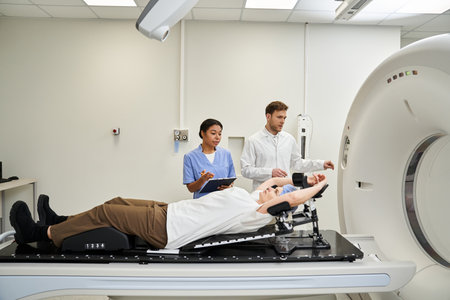 Handsome doctor and nurse assist female patient as MRI scan awaits in a modern facility.の写真素材