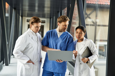 Three healthcare professionals engage in a discussion while reviewing a digital report.の写真素材