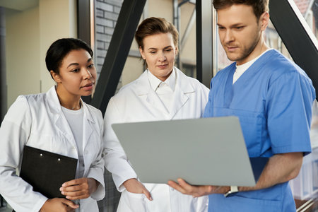 Three diverse healthcare professionals discuss patient care in a contemporary hospital environment.の写真素材