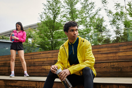 Two sporty individuals take a break, enjoying the fresh air and relaxation after exercising.