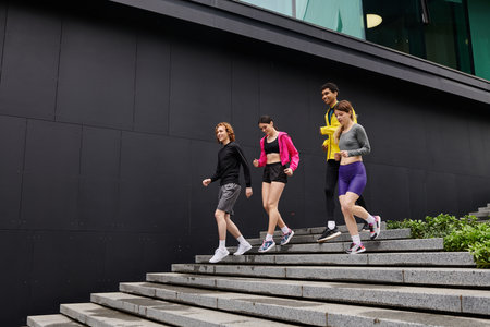 Four athletes jog down wide stairs, showcasing their colorful athletic outfits.の写真素材