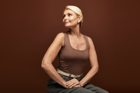 Beautiful senior woman poses elegantly, showcasing her poise and charm in a cozy studio atmosphere.の写真素材