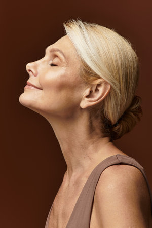 Beautiful senior woman with closed eyes embodies tranquility in a soft light, radiating grace.の写真素材