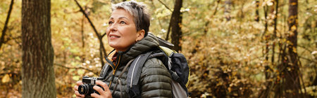 A senior woman enjoys her hike in the serene forest, capturing the vibrant autumn colors.