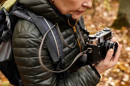 A senior woman enjoys a peaceful hike in the forest, capturing natures beauty with her camera.の写真素材