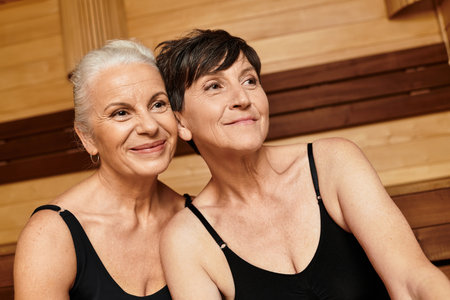 Two beautiful mature women enjoy each others company at a serene wellness center.の写真素材