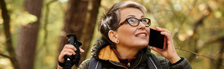 A senior woman explores a vibrant forest trail, enjoying a call in natures embrace.の写真素材