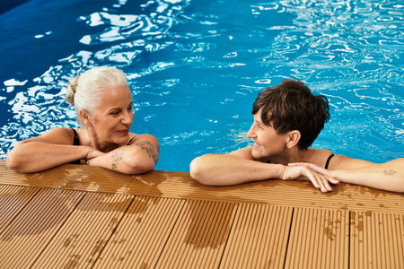 Two active and beautiful mature women enjoy a tranquil moment together in a spa pool.