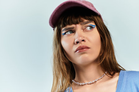 Young woman showcases her unique fashion sense with bold makeup and a fashionable cap.の写真素材