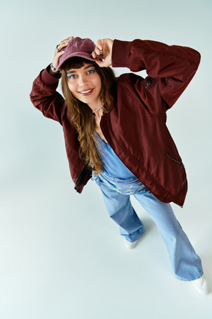 A young woman in trendy attire poses playfully, expressing her unique sense of style vividly.