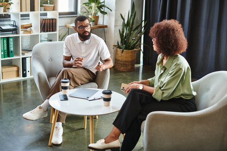 Two young professionals discuss job opportunities in a stylish studio environment.