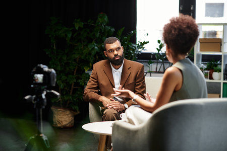 A young woman interviews with a man in a modern studio, both engaged in conversation.の写真素材