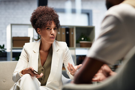 In a modern studio setting, a young woman interviews a male candidate, discussing opportunities.の写真素材