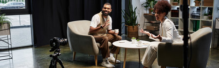 Two young professionals converse in a stylish studio setting while preparing for a interview.