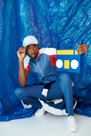Handsome young man poses confidently against a striking blue backdrop, showcasing his style.