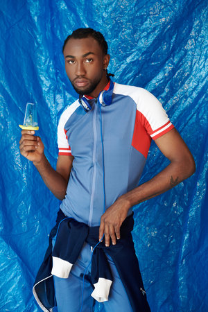 A stylish young man in blue holds a vibrant popsicle, exuding charm.
