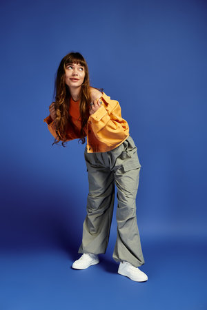 A young woman in fashionable clothing strikes a fun pose, expressing modern style and grace.