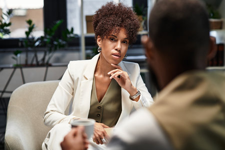 Two young professionals engage in a thoughtful interview while seated in a stylish studio.の写真素材