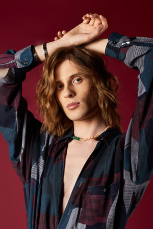 A stylish young man with long hair confidently sports a trendy shirt and accessories.