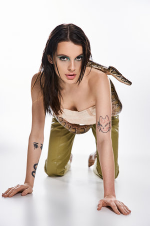 Striking young woman gracefully interacts with a snake, showcasing her confidence and allure.