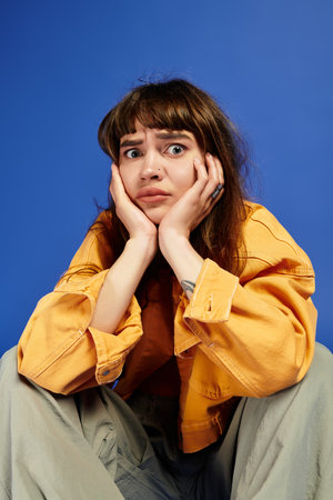 Stylish woman with a pensive expression combines casual attire and striking colors in her look.
