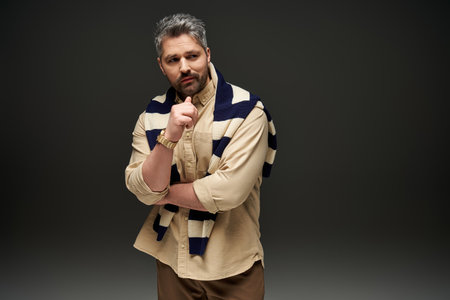 Handsome man poses confidently in a chic outfit, exuding trendy elegance in a studio.