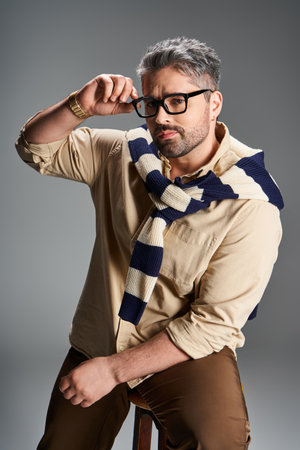 Handsome man in glasses showcases effortless style and charm in a trendy studio environment.