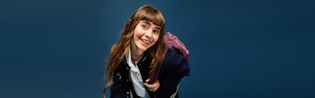 A young woman smiles brightly while holding her backpack, showcasing her enthusiasm for learning.