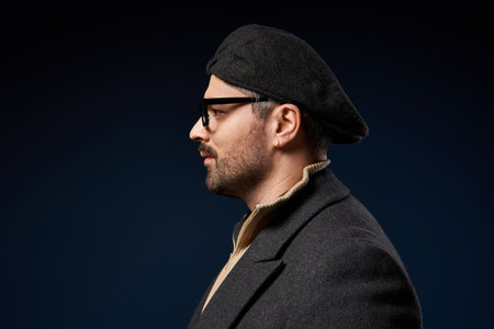 A fashionable man wearing glasses and a beret poses confidently in an elegant outfit.の写真素材