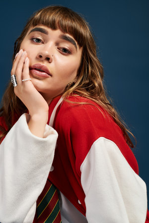 A carefree young woman rests her chin on her hand, looking thoughtful in casual attire.