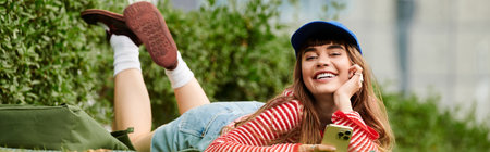 Brightly dressed student lounges happily on the grass, engaging with her smartphone in a park.
