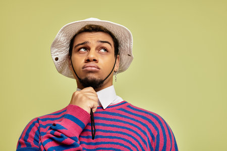 A stylish young man poses thoughtfully in an abstract striped sweatshirt, showcasing unique fashion.の写真素材