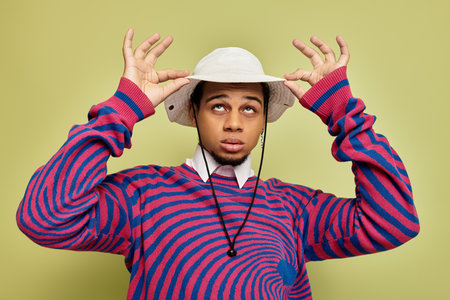 A young african american man wears a trendy striped sweatshirt while posing with enthusiasm.